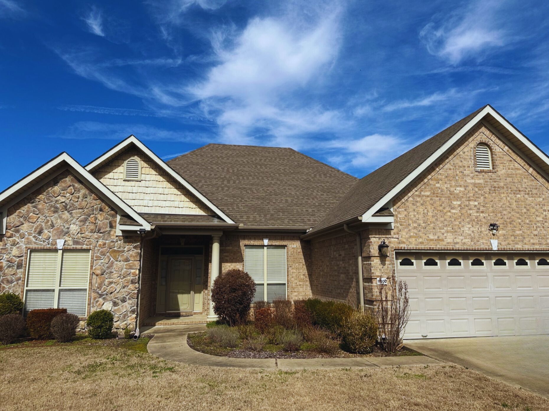 A large brick house with a garage and a blue sky in the background