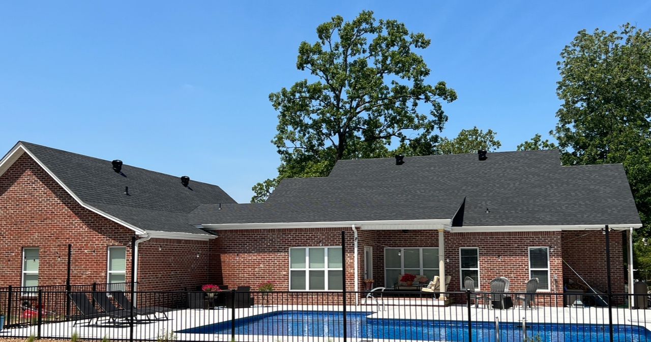 A brick house with a pool in front of it