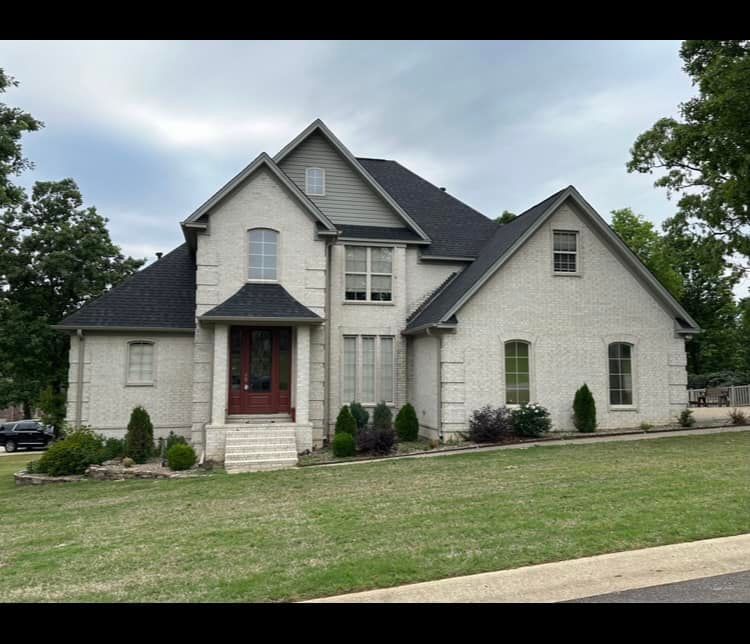A large white brick house with a black roof