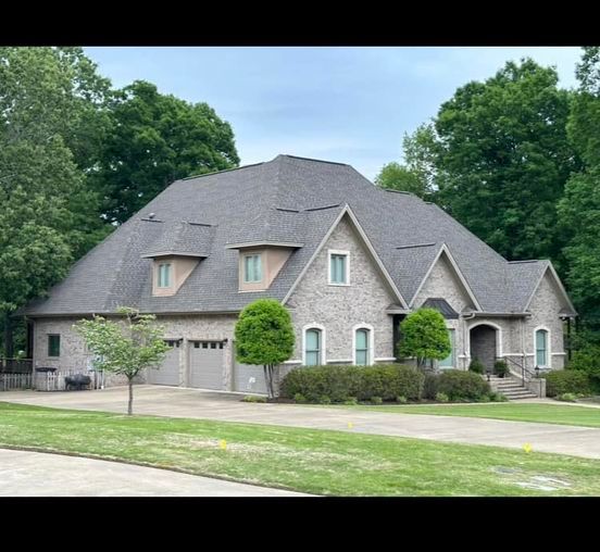 A large house with a gray roof is surrounded by trees