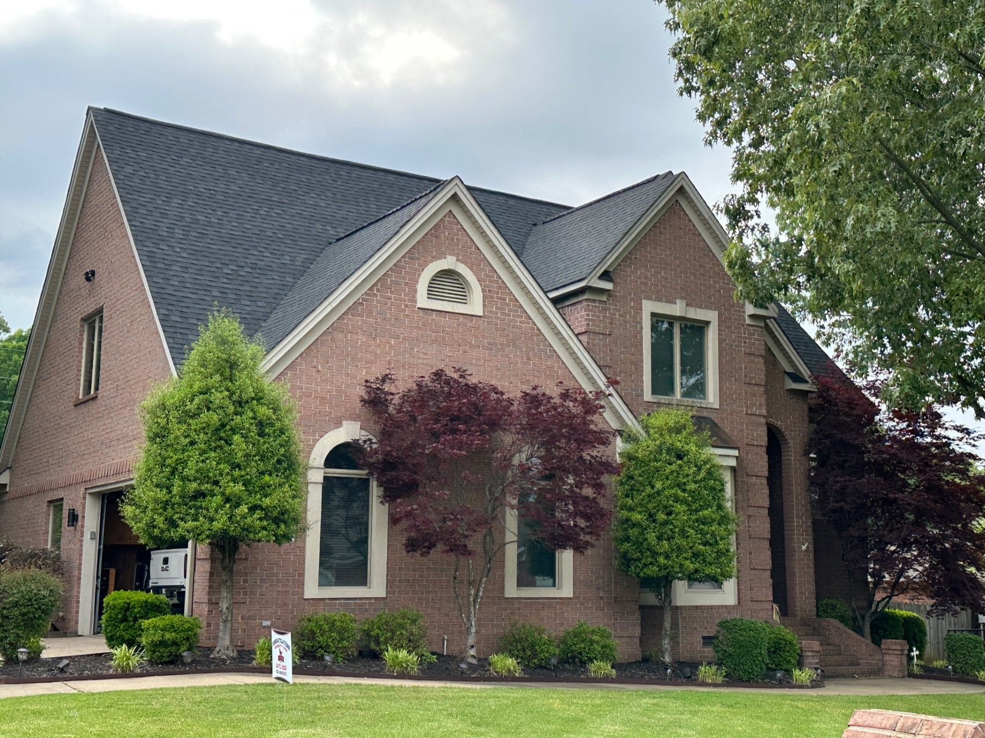 A large brick house with a black roof is for sale.