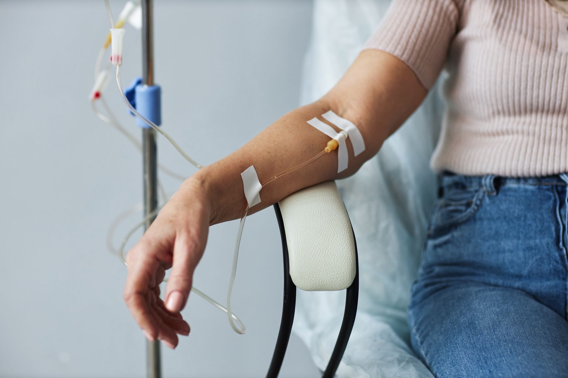 Eine Frau sitzt in einem Krankenhausstuhl mit einer Infusion im Arm