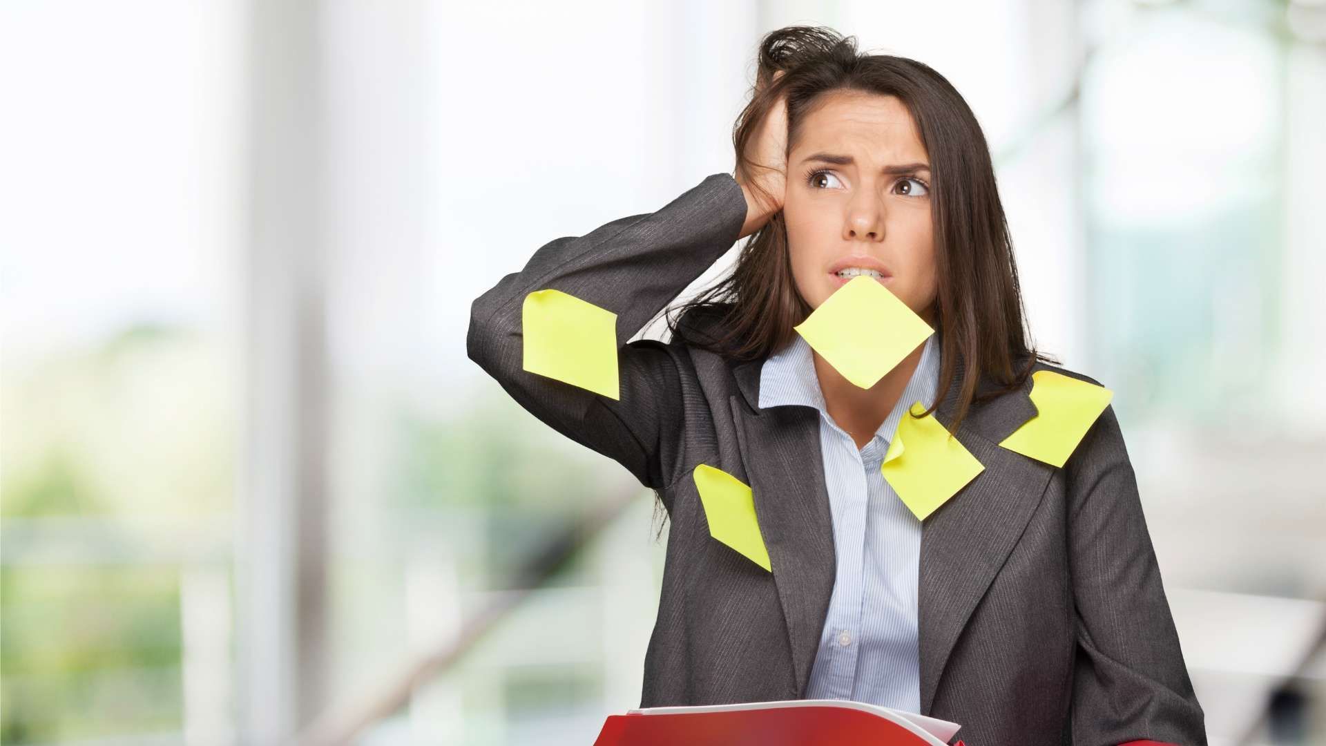 Businesswoman looking worried with sticky notes on her face and suit in an office setting