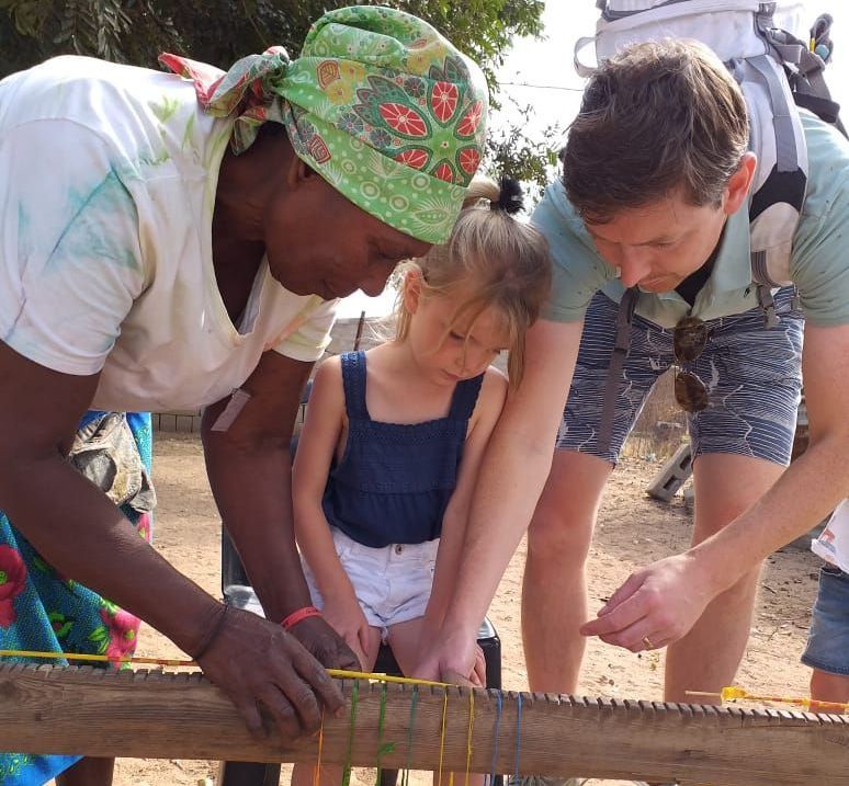 A woman wearing a green headband is cutting a piece of wood