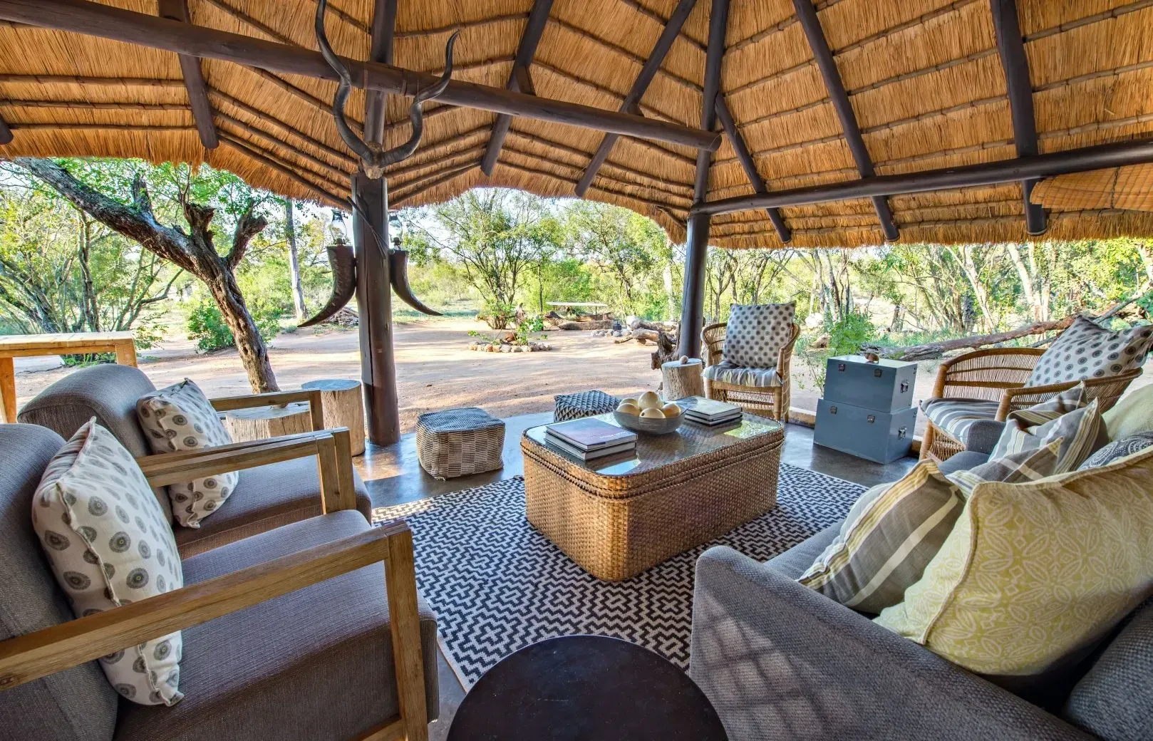 A living room filled with furniture under a thatched roof.