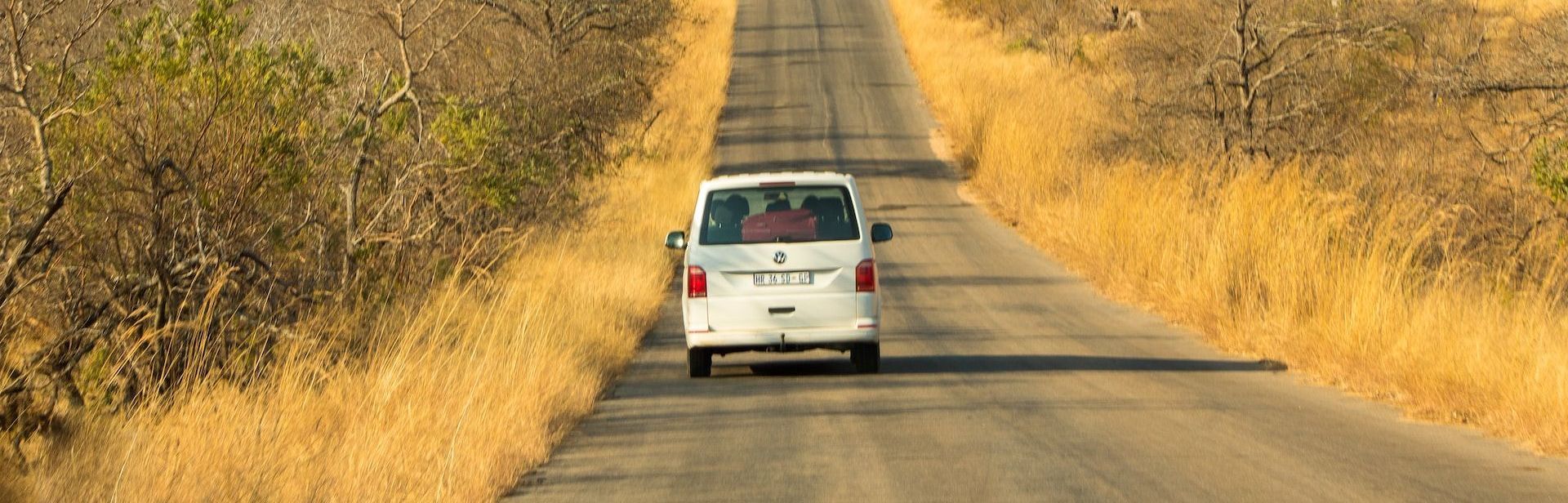 A white van is driving down a dirt road.