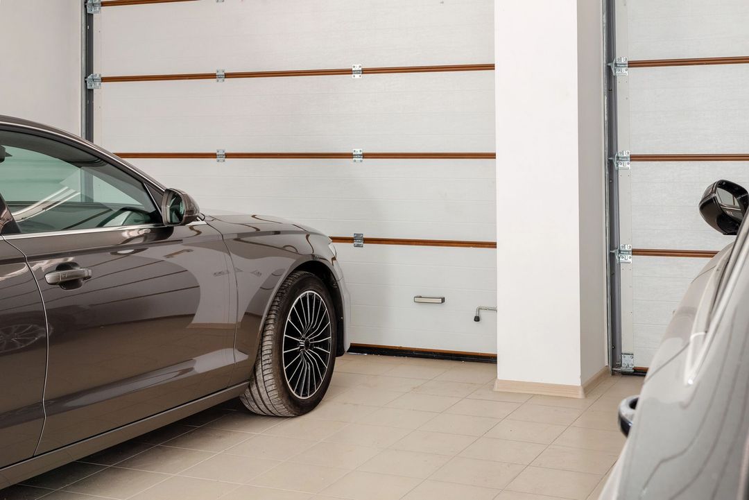 Un'auto marrone parcheggiata in un garage accanto a un pilastro bianco, con le porte sezionali del garage chiuse sullo sfondo.