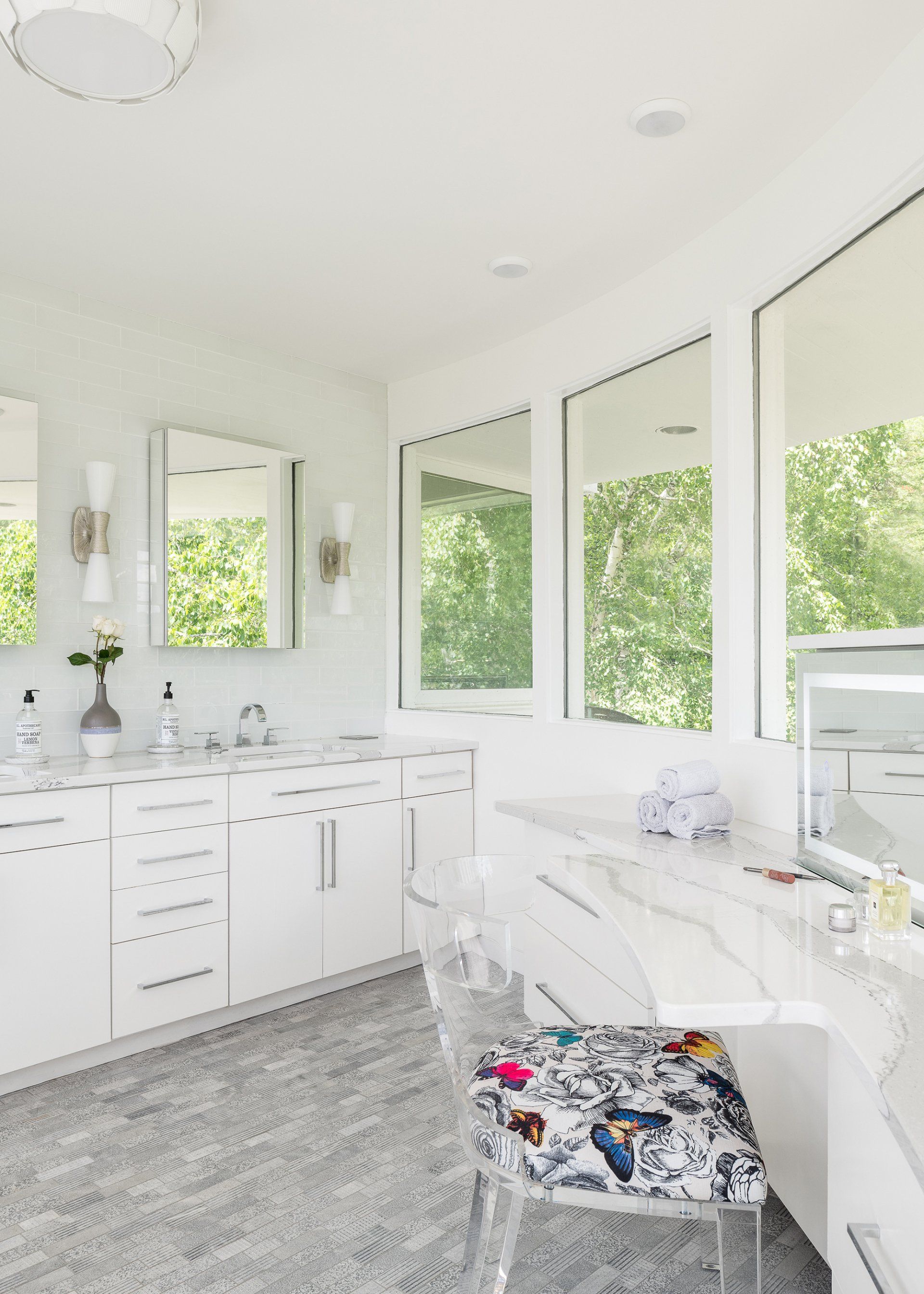 A bathroom with two sinks , a vanity , and a chair.