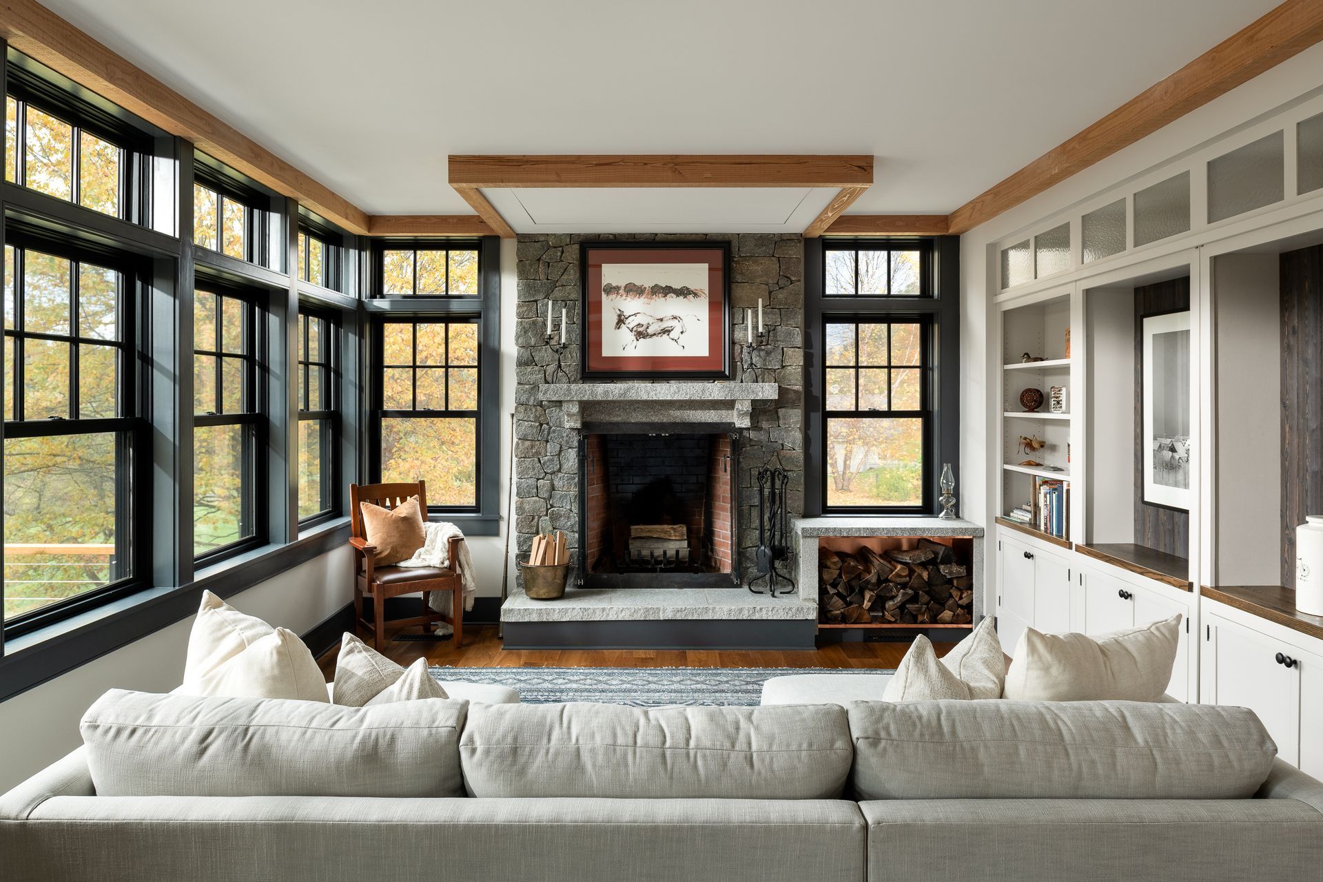 A living room with a couch , fireplace , and lots of windows.