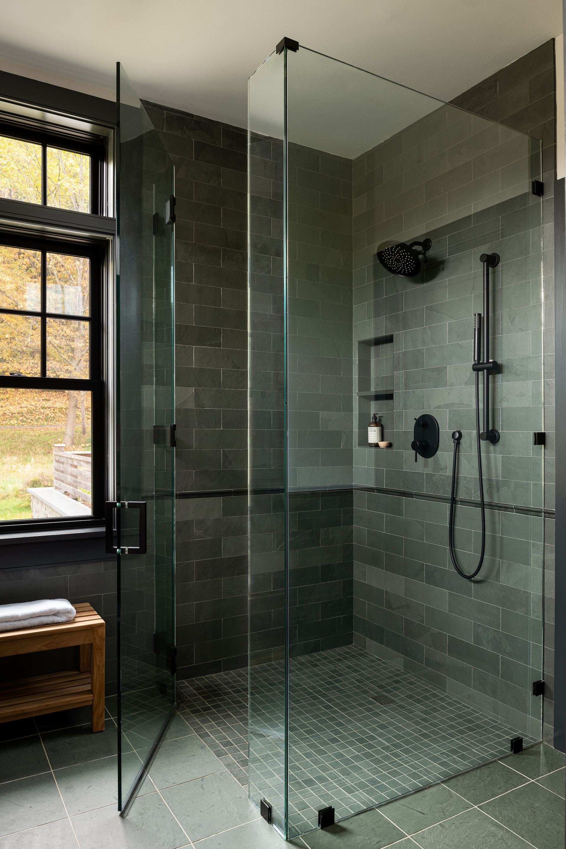 A bathroom with a walk in shower and a window.