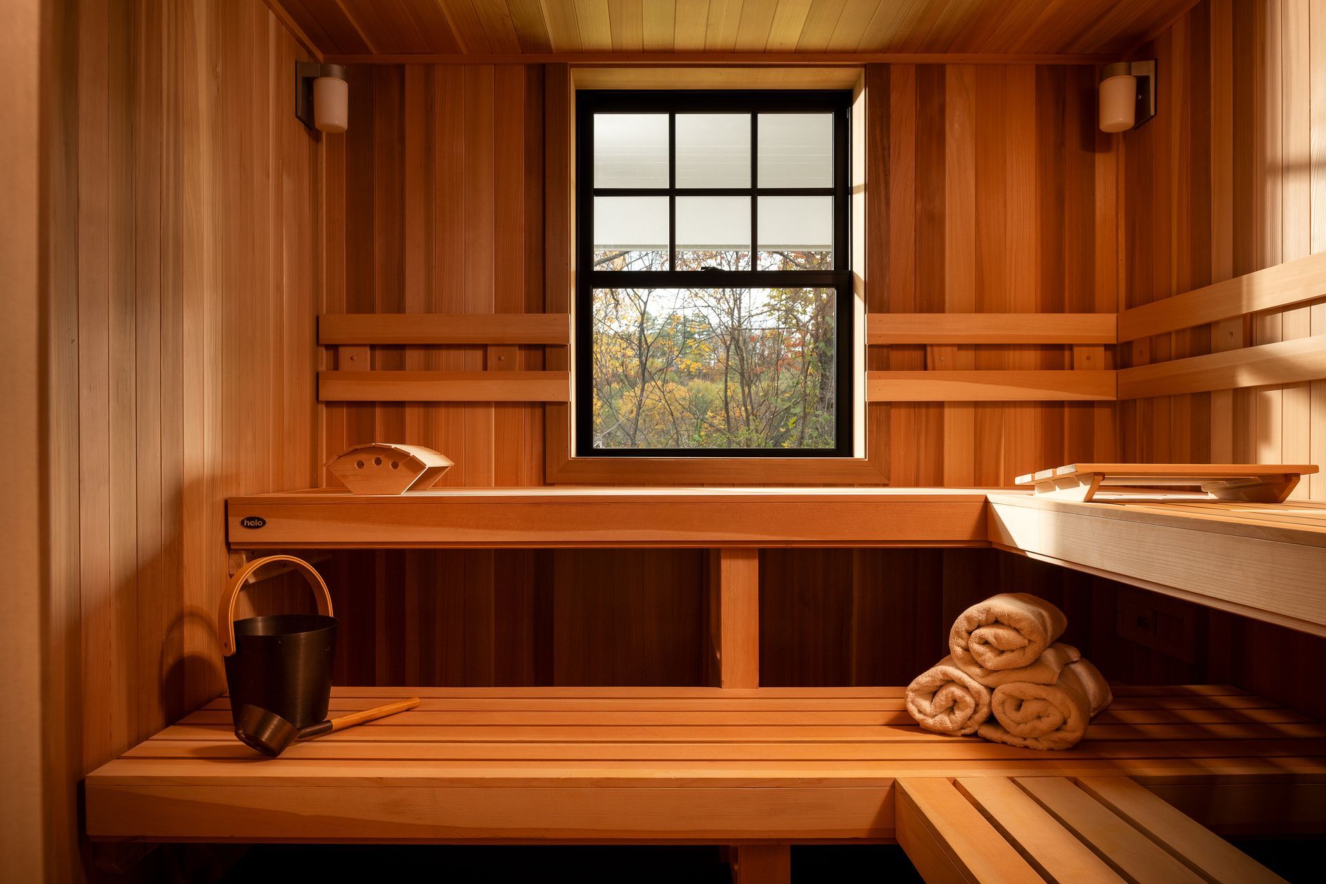 A wooden sauna with a window and towels on the benches