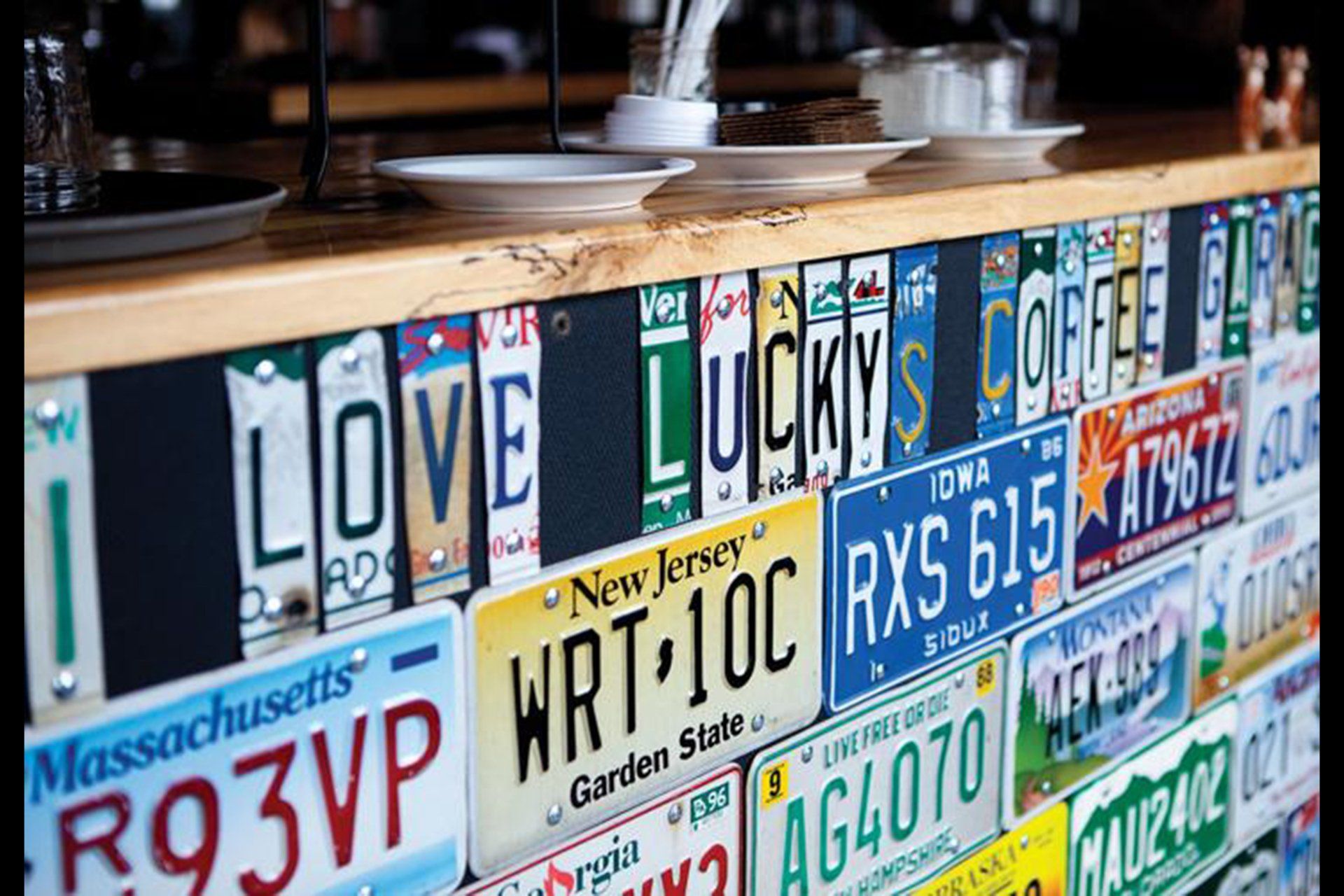 A row of license plates are lined up on a counter with the words `` love lucky '' written on them.