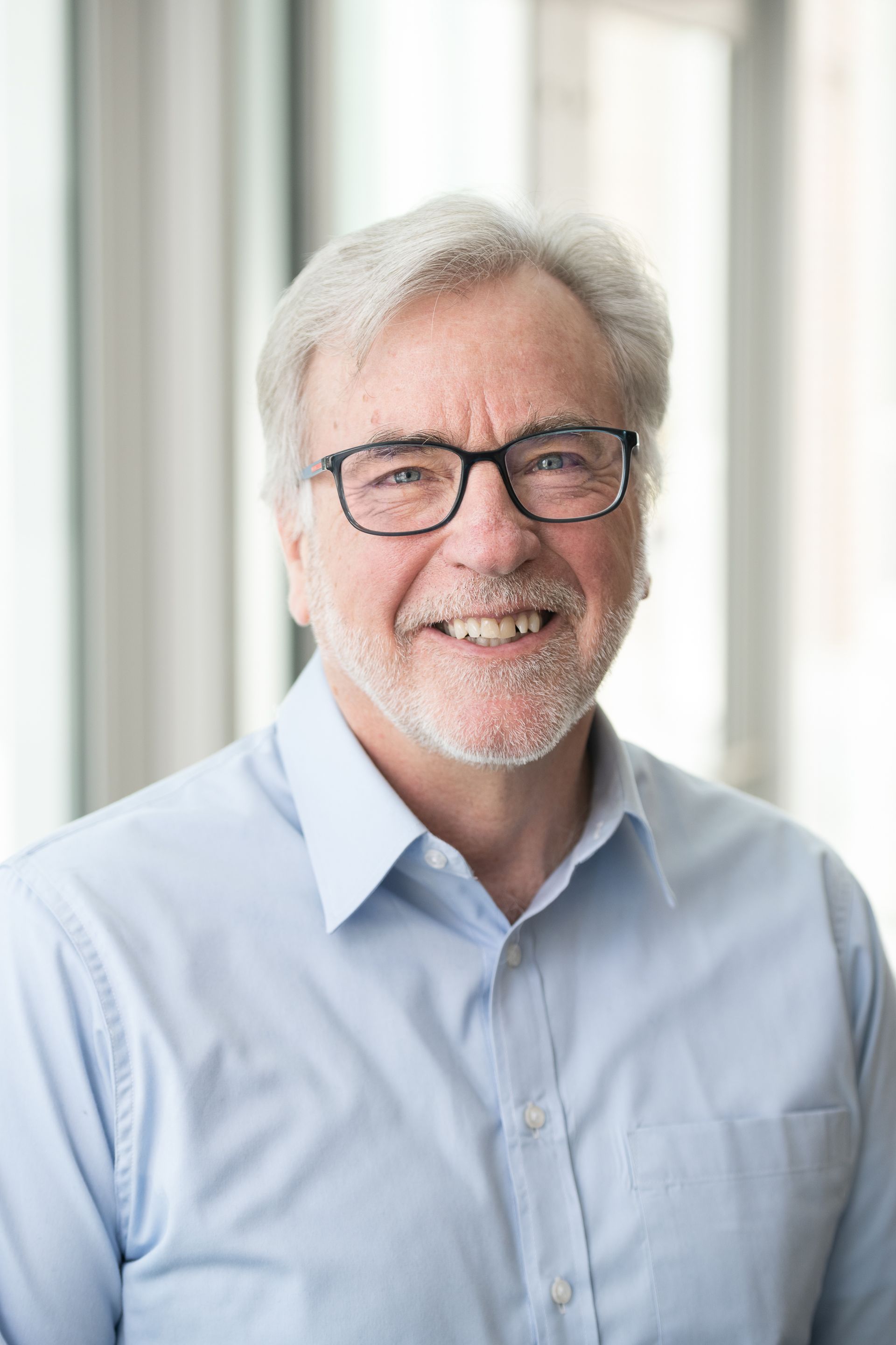 A man with glasses and a beard is smiling for the camera.
