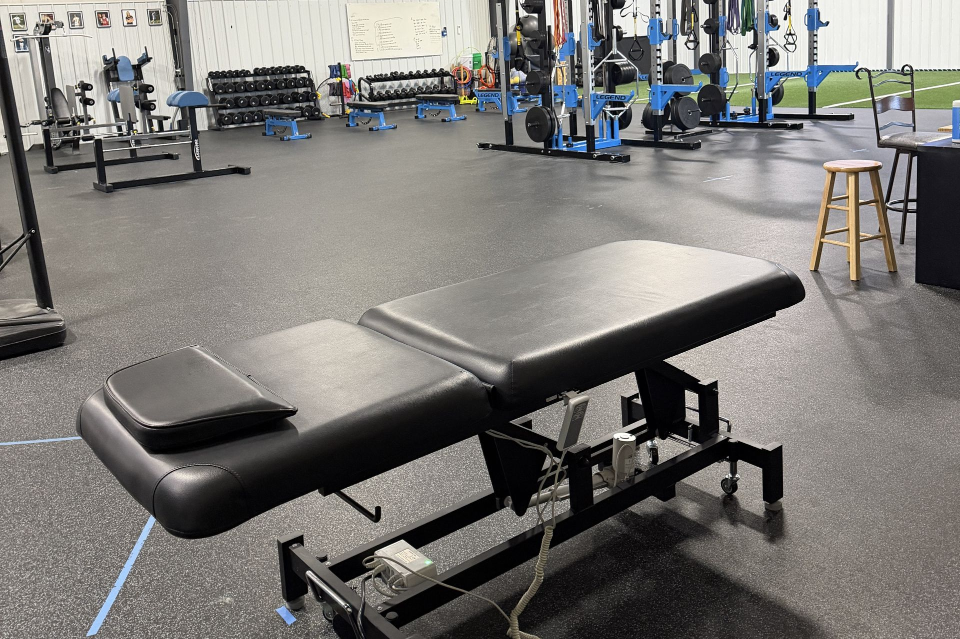 Massage table in a gym with weight racks and a 