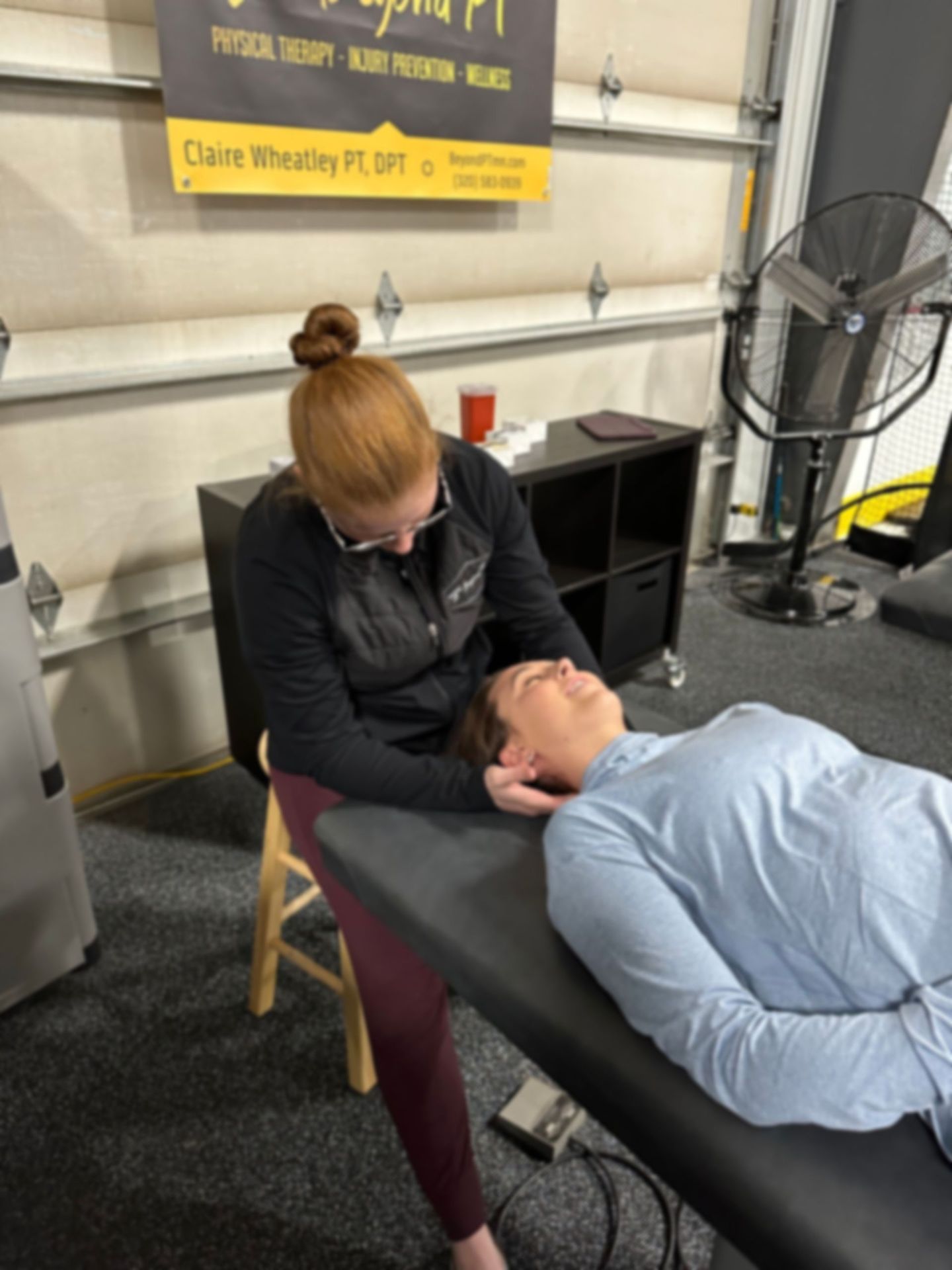 A physical therapist performs neck manipulation on a patient lying on a table.