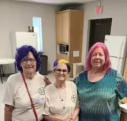 three women are posing for a picture in a kitchen .