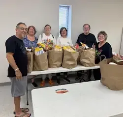 a group of people are standing around a table filled with bags of food .