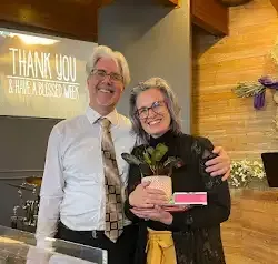 a man and a woman are standing next to each other holding a potted plant .