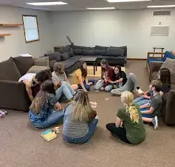 a group of people are sitting in a circle on the floor in a living room .