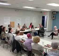 a group of people are sitting at tables in a room .