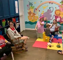 a group of people are sitting in a room with a mural on the wall .