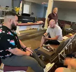 a group of men are sitting in chairs in a church talking to each other .