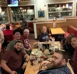 a group of men are sitting at a table in a restaurant .