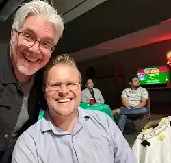 two men are posing for a picture together in a room .