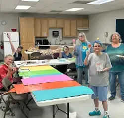 a group of people are standing around a table in a kitchen .