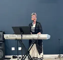 a woman is standing in front of a keyboard and singing into a microphone .