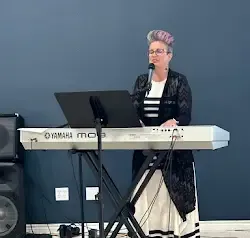 a woman is standing in front of a keyboard and singing into a microphone .
