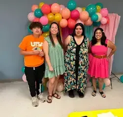 a group of people are posing for a picture in front of balloons .