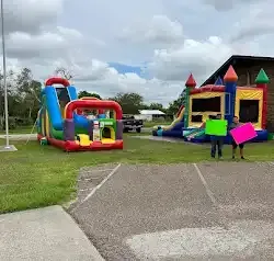 a group of people holding signs in front of a bouncy house .