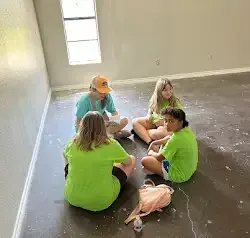 a group of young girls are sitting on the floor in a room .