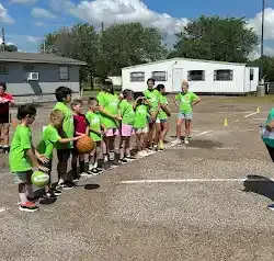 a group of children are standing in a parking lot holding basketballs .