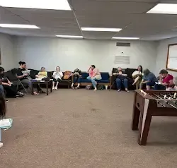 a group of people are sitting around a foosball table in a room .