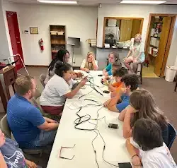a group of people are sitting around a table in a room .