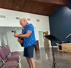 a man is playing a guitar in a room with chairs .