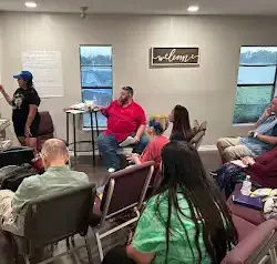 a group of people are sitting in chairs in a room .