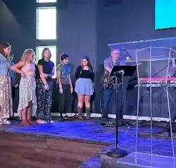 a group of people are standing on a stage in front of a microphone .