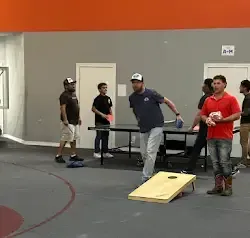 a group of men are playing a game of cornhole in a gym .