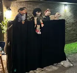 a group of puppets are sitting on top of a black curtain .