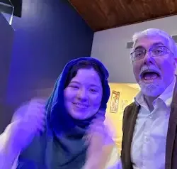 a man and a woman are standing next to each other in a room with purple lights .