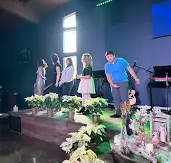 a group of people are standing on a stage with flowers .
