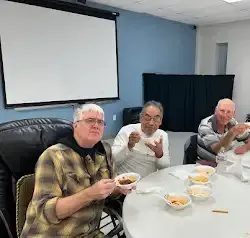 a group of men are sitting at a table eating food .