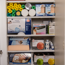 Shelves stocked with medical supplies, masks, boxes, bottles, and colorful balls in a cabinet