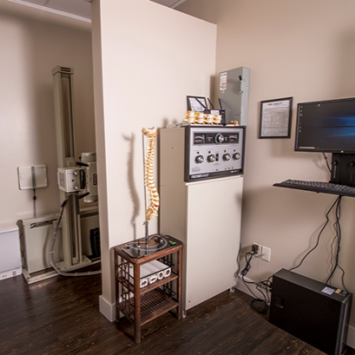 Lab equipment and control panel in a room with a mounted monitor and cables.