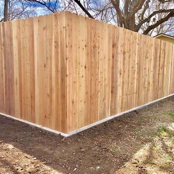 Wooden privacy fence with a peaked top along a dirt and grass yard corner