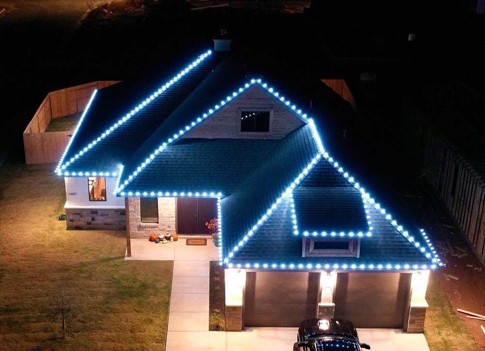 Suburban house at night outlined with bright blue Christmas lights.