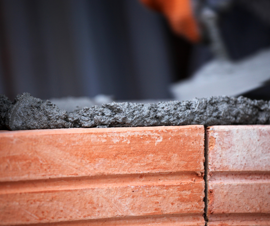 A brick wall is being built with concrete being poured on top of it.
